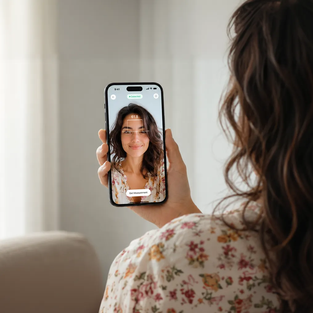 Person holding an iPhone at arm's length while the app measures the distance between their pupils