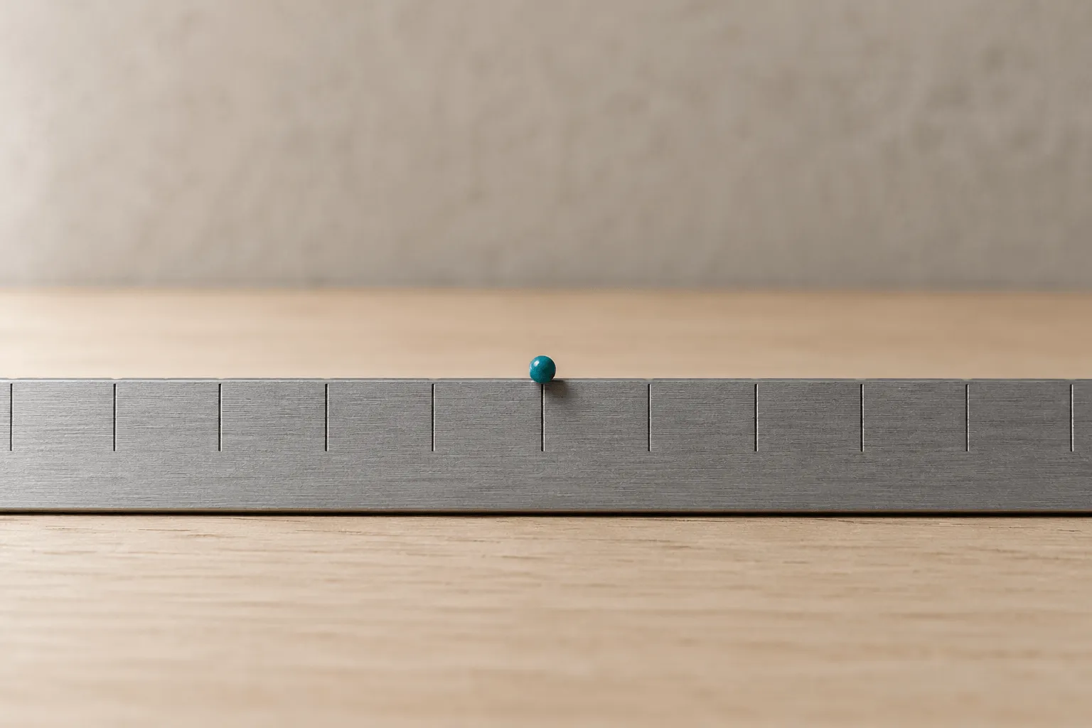 Macro of a steel rule's millimetre ticks with a marker resting midway between two of them